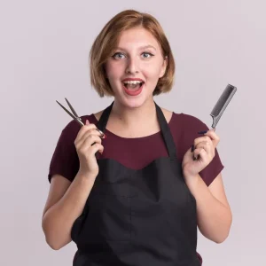 happy-young-beautiful-woman-hairdresser-apron-holding-hair-comb-scissors-looking-front-smiling-standing-white-wall_141793-64745
